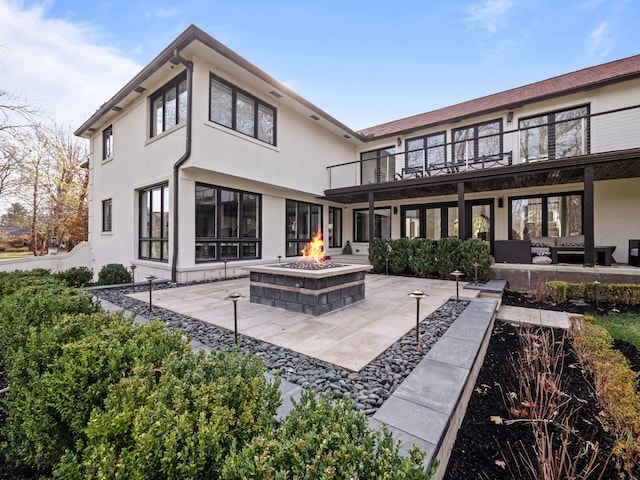 rear view of house featuring a fire pit, a patio, a balcony, and stucco siding