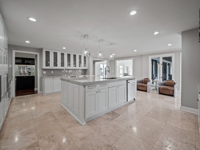 kitchen with white cabinets, an island with sink, glass insert cabinets, open floor plan, and a sink