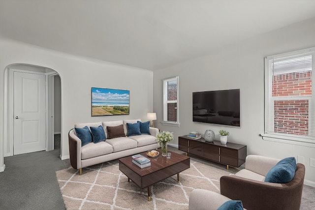 carpeted living area featuring baseboards and arched walkways