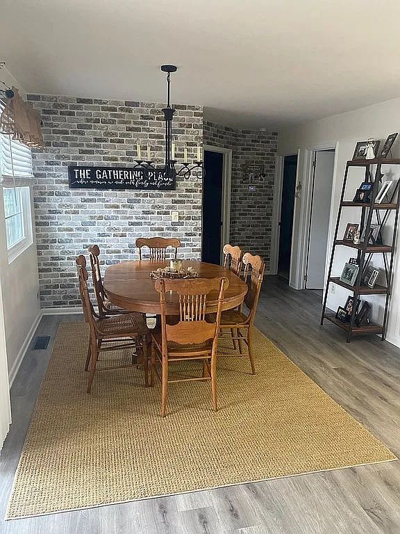 dining space with brick wall and hardwood / wood-style floors