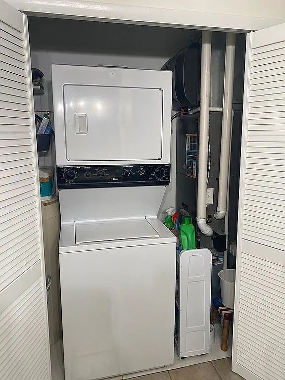 washroom with stacked washer and clothes dryer and light tile patterned floors