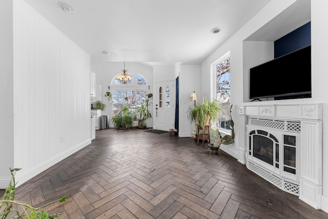 unfurnished living room with baseboards, a tile fireplace, and an inviting chandelier