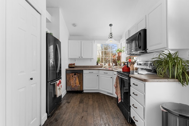 kitchen featuring dark countertops, dark wood-style flooring, decorative light fixtures, black appliances, and white cabinetry