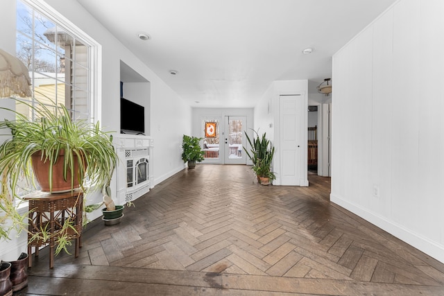 unfurnished living room with baseboards, french doors, and a glass covered fireplace