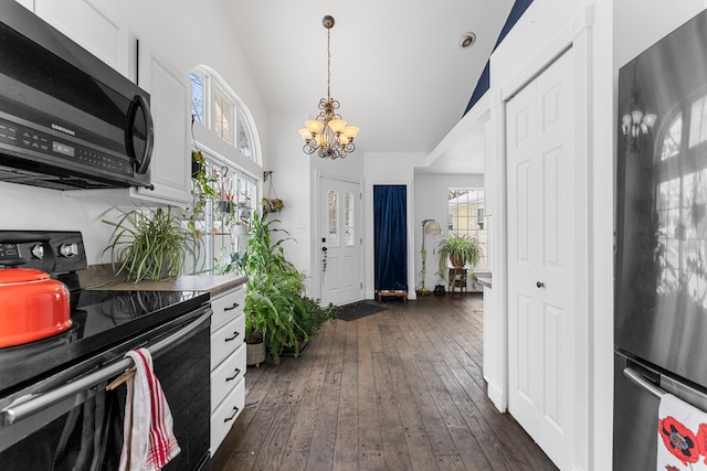 kitchen featuring dark wood-type flooring, freestanding refrigerator, white cabinetry, vaulted ceiling, and black / electric stove