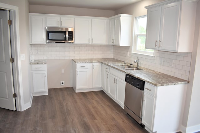 kitchen featuring sink, light stone counters, appliances with stainless steel finishes, dark hardwood / wood-style flooring, and white cabinets