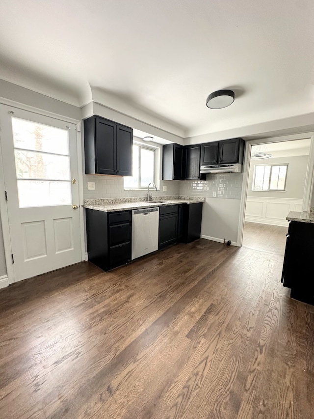 kitchen with sink, light stone counters, dark hardwood / wood-style floors, stainless steel dishwasher, and tasteful backsplash