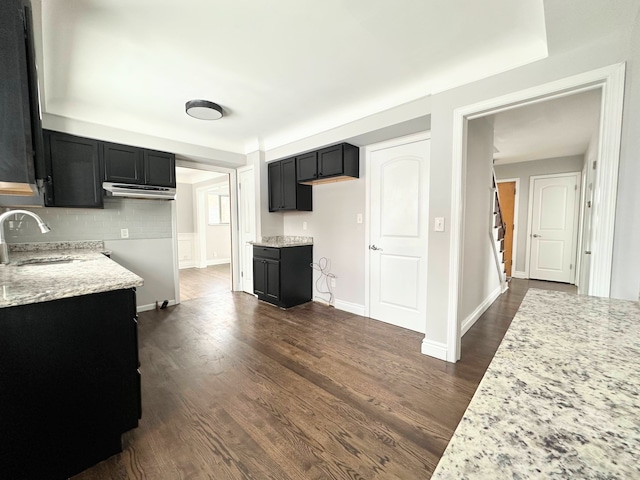 kitchen featuring sink, dark wood-type flooring, backsplash, and light stone countertops