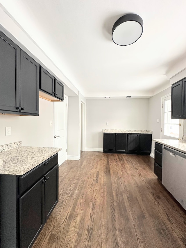 kitchen with stainless steel dishwasher, dark hardwood / wood-style floors, and light stone counters