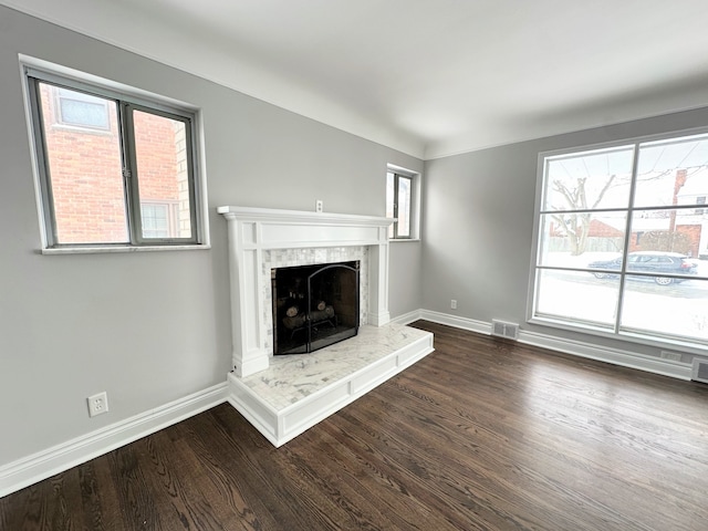 unfurnished living room featuring a tiled fireplace and dark hardwood / wood-style floors