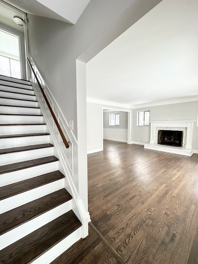 unfurnished living room featuring a premium fireplace and dark wood-type flooring