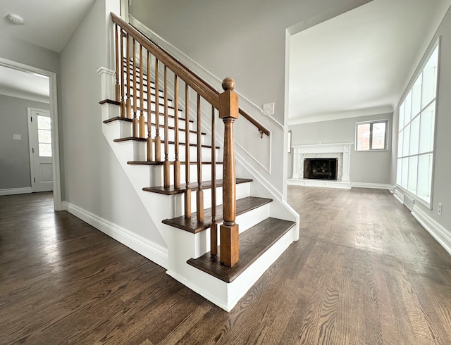 stairs featuring a healthy amount of sunlight, wood-type flooring, and a fireplace