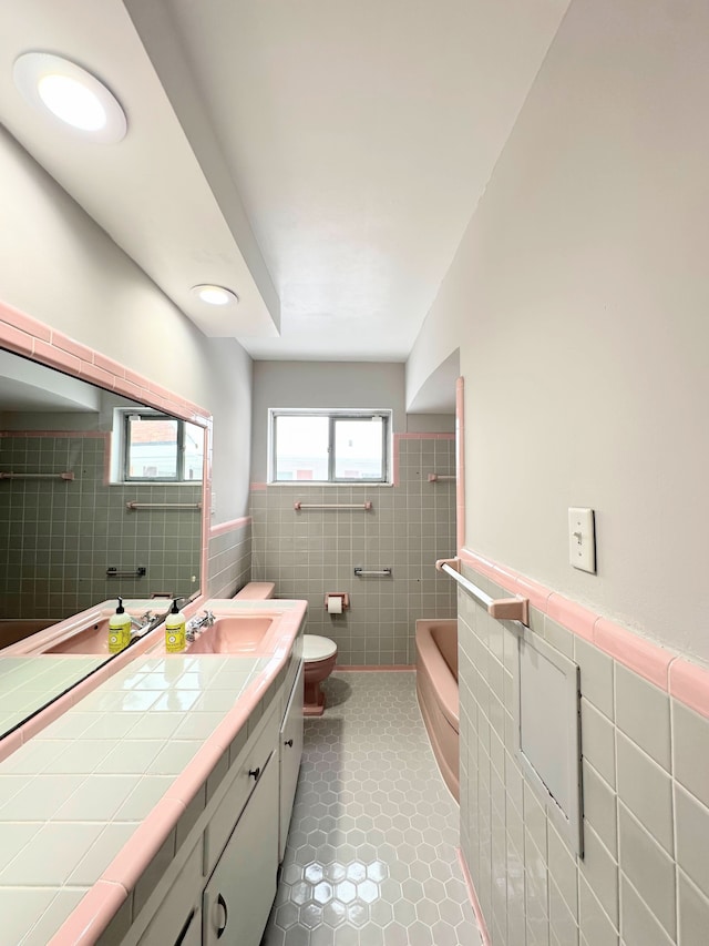 full bathroom featuring tile walls, vanity, tiled shower / bath combo, tile patterned flooring, and toilet