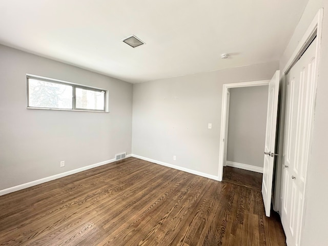 unfurnished bedroom with a closet and dark hardwood / wood-style floors