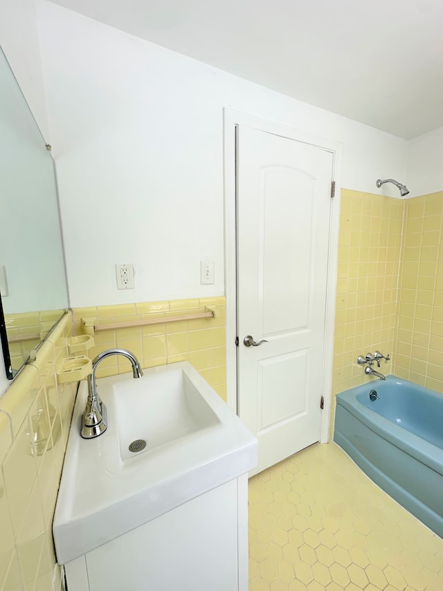 bathroom with sink, tile walls, and tiled shower / bath