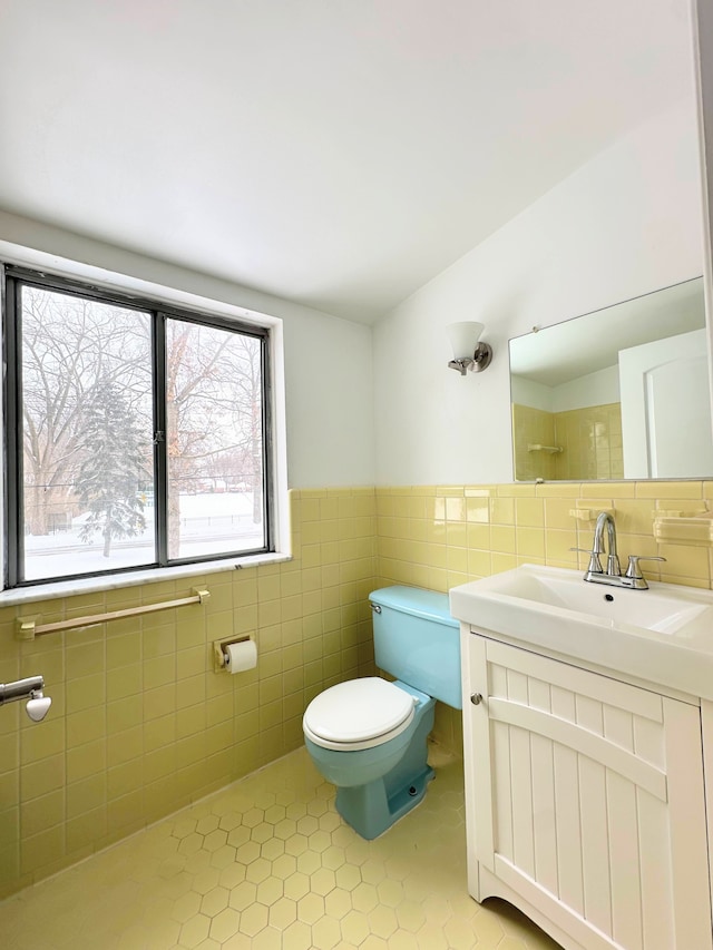 bathroom with lofted ceiling, tile patterned floors, toilet, tile walls, and vanity