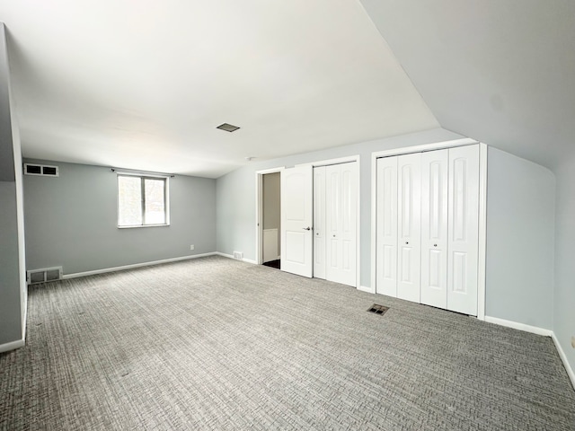 unfurnished bedroom with carpet floors, lofted ceiling, and multiple closets