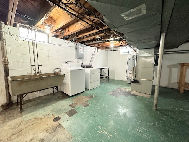 basement featuring washing machine and dryer, sink, heating unit, and electric panel