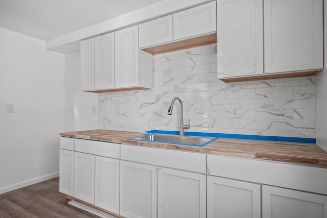 kitchen featuring butcher block countertops, white cabinets, decorative backsplash, dark hardwood / wood-style flooring, and sink