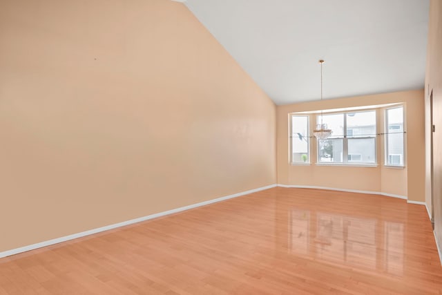 spare room with lofted ceiling, light wood-style floors, and baseboards