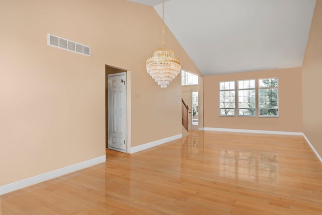 unfurnished living room featuring a notable chandelier, visible vents, light wood-style floors, high vaulted ceiling, and baseboards