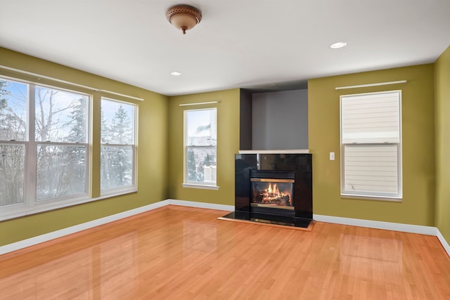 unfurnished living room with a tile fireplace, recessed lighting, baseboards, and wood finished floors