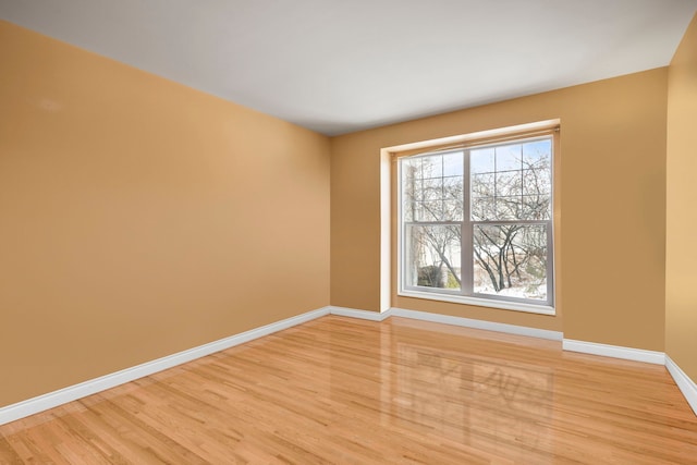 spare room featuring light wood-type flooring and baseboards