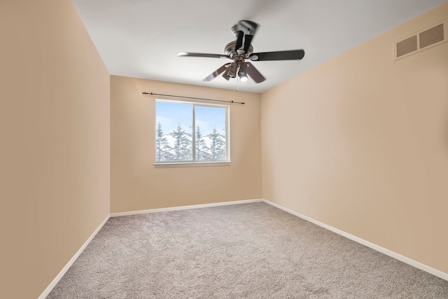 spare room featuring carpet floors, a ceiling fan, visible vents, and baseboards