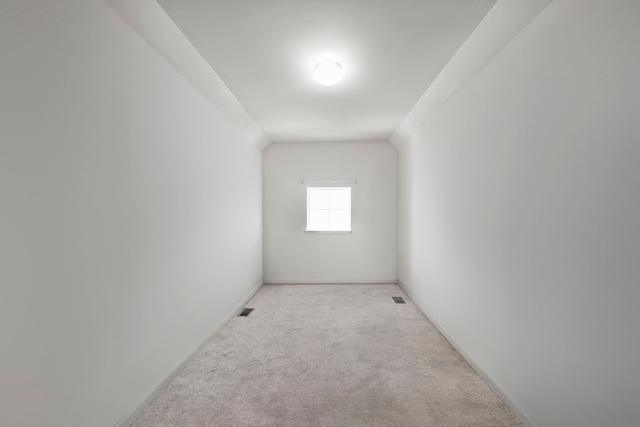 spare room featuring light colored carpet, visible vents, and baseboards