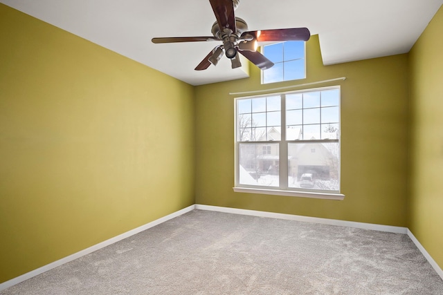 carpeted spare room with a ceiling fan and baseboards