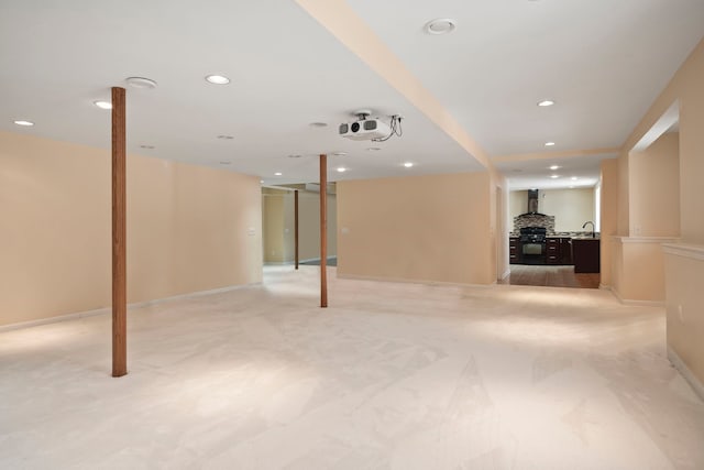 finished below grade area with baseboards, light colored carpet, a sink, and recessed lighting