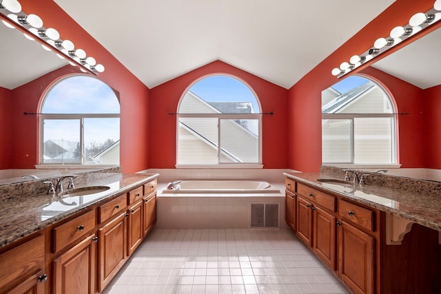 bathroom featuring lofted ceiling, visible vents, two vanities, and a sink