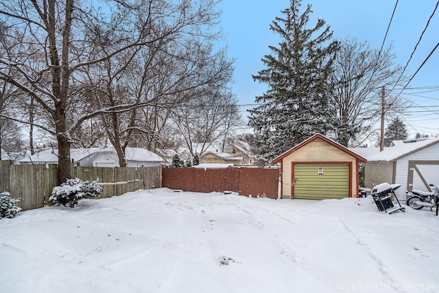 snowy yard featuring an outbuilding and a garage