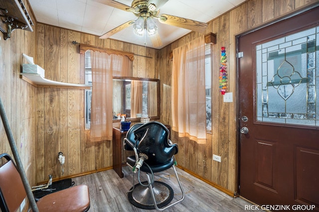 entrance foyer with light hardwood / wood-style flooring, ceiling fan, and wood walls