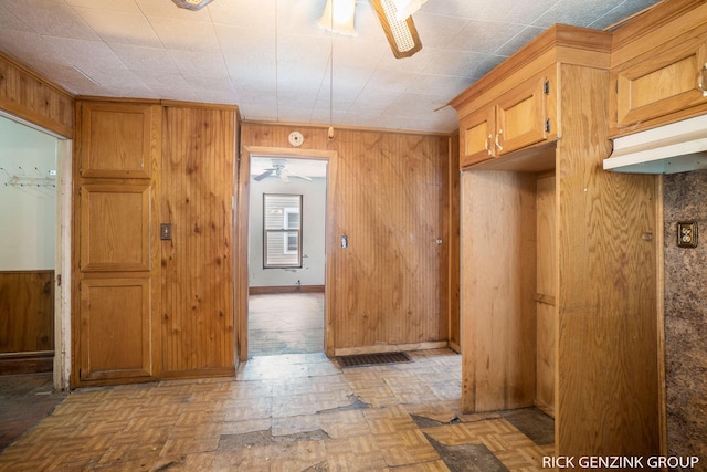 interior space featuring ceiling fan, light parquet flooring, and wood walls