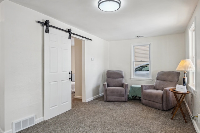 sitting room with baseboards, a barn door, visible vents, and carpet flooring