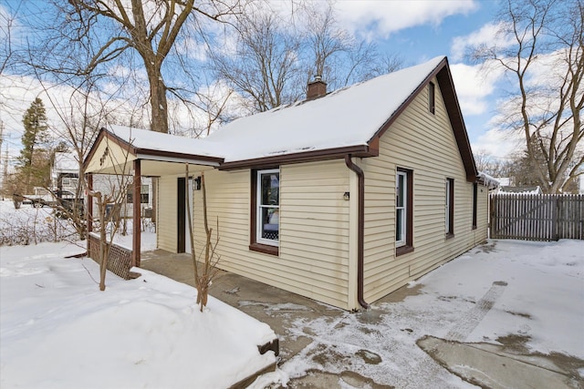 view of snow covered exterior featuring fence and a chimney