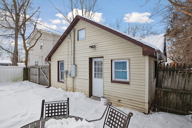 snow covered rear of property with fence