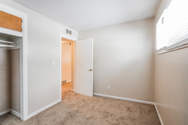 unfurnished bedroom with a closet and light colored carpet