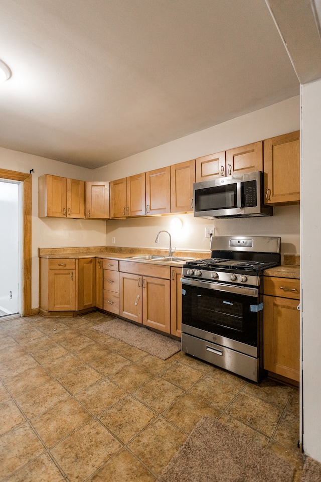 kitchen with appliances with stainless steel finishes, sink, and light brown cabinets