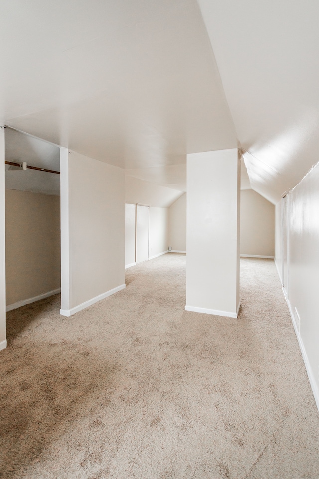 bonus room with light carpet and vaulted ceiling