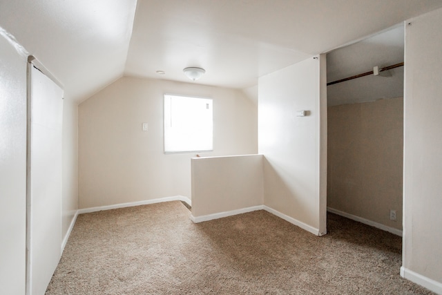 additional living space featuring vaulted ceiling and light colored carpet