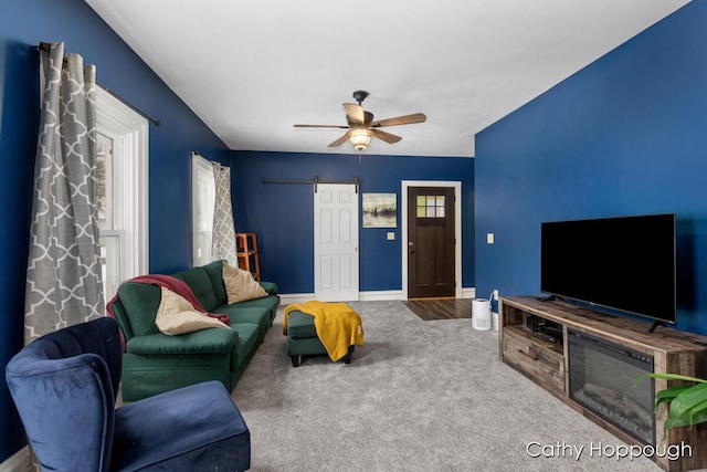 carpeted living room featuring a barn door and ceiling fan