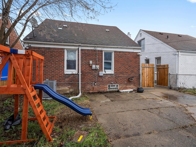 rear view of property with a playground and central air condition unit