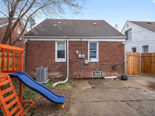 rear view of house with a playground and central AC unit