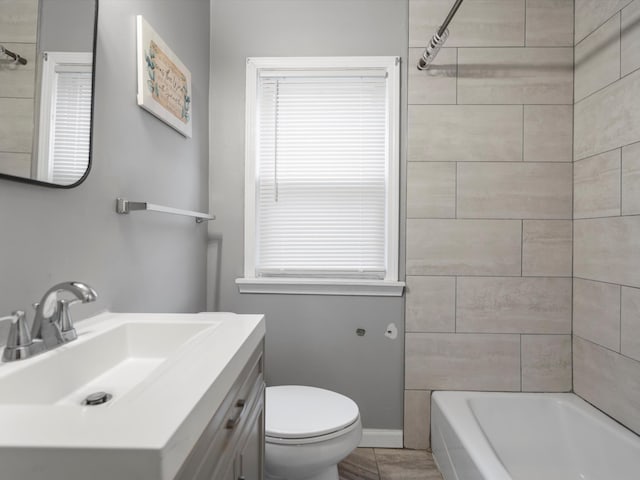 full bathroom featuring tiled shower / bath, vanity, and toilet