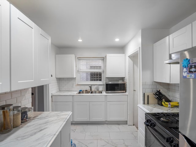 kitchen featuring tasteful backsplash, sink, white cabinets, and appliances with stainless steel finishes