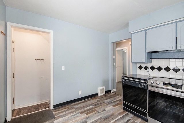 kitchen with stainless steel electric range, decorative backsplash, black dishwasher, and hardwood / wood-style flooring