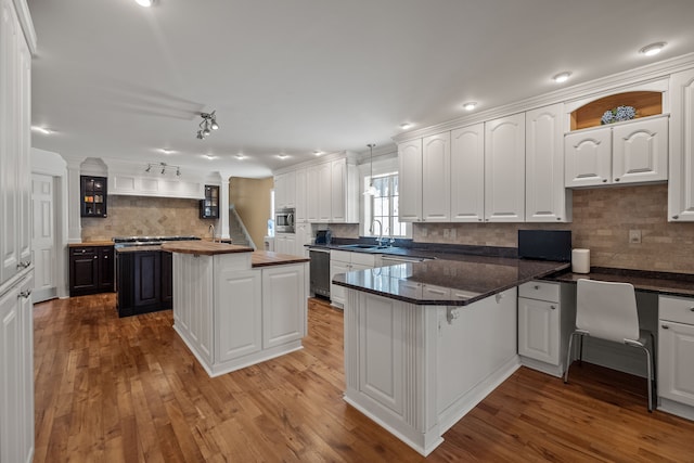 6705 College Park, Clarkston, MI 48346 - kitchen with white cabinets, a sink, a peninsula, stainless steel appliances, and backsplash