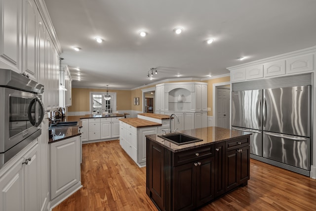 6705 College Park, Clarkston, MI 48346 - kitchen featuring a kitchen island with sink, built in appliances, a sink, and crown molding